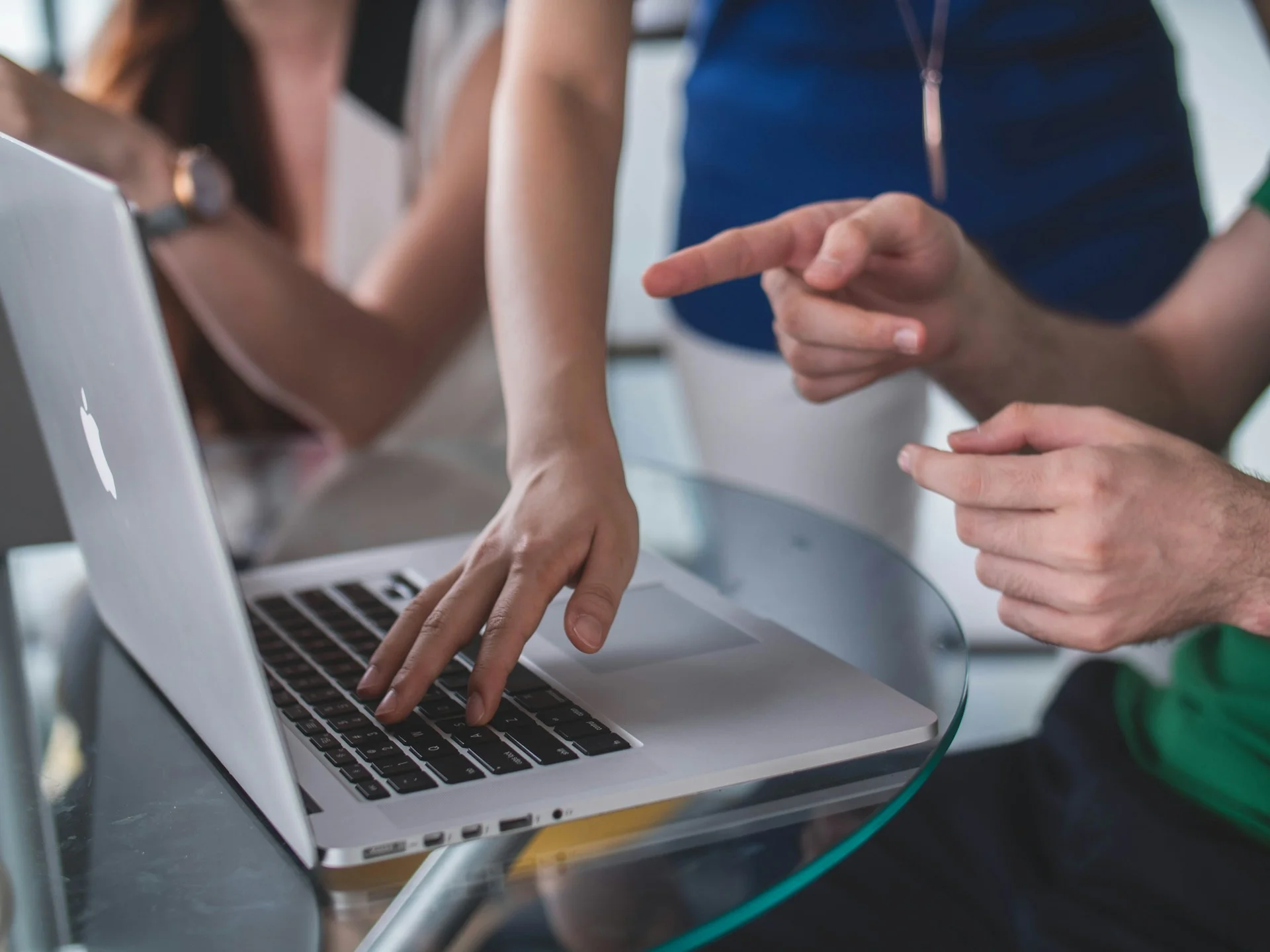 Close-up of two people collaborating on a laptop, pointing and typing.